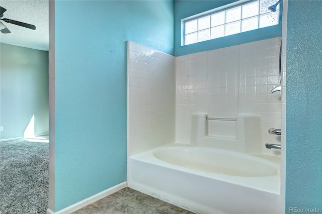 full bath featuring tub / shower combination, ceiling fan, baseboards, a textured wall, and a textured ceiling