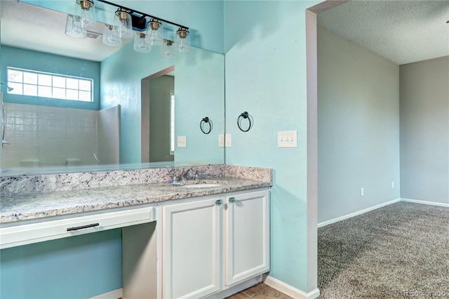 bathroom with a textured ceiling, vanity, and baseboards