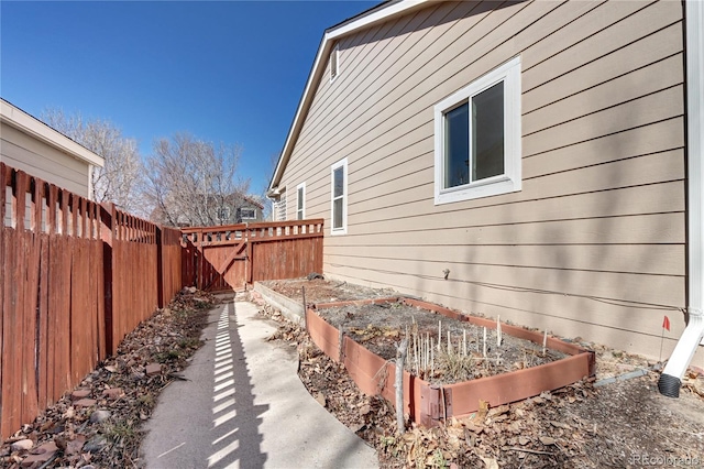 view of home's exterior featuring a vegetable garden and fence