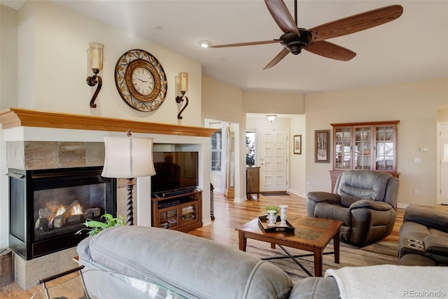 living room with ceiling fan, a fireplace, and light hardwood / wood-style flooring