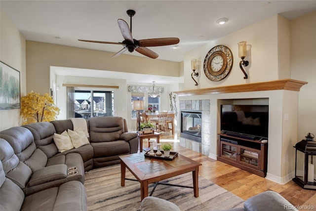 living room featuring a tile fireplace, ceiling fan, and light hardwood / wood-style flooring