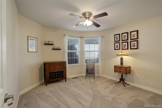 living area featuring light carpet and ceiling fan