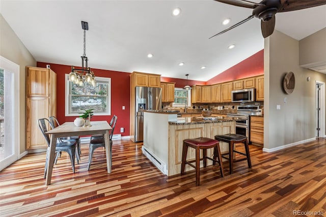 kitchen with plenty of natural light, vaulted ceiling, stainless steel appliances, and a center island