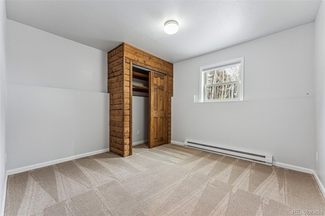 unfurnished bedroom with a baseboard heating unit, a closet, carpet floors, and baseboards