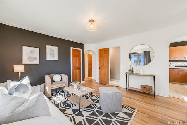 living room featuring light wood-type flooring, arched walkways, and baseboards