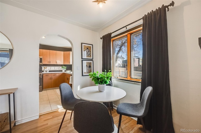 dining area featuring light wood finished floors and arched walkways