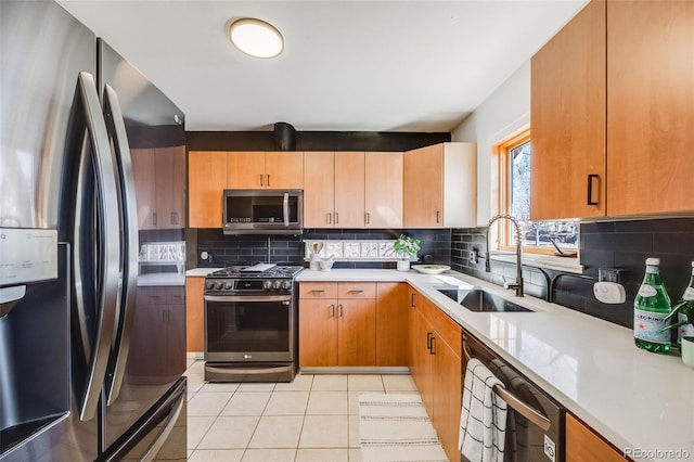 kitchen with stainless steel appliances, backsplash, a sink, and light countertops