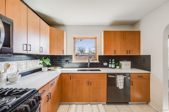 kitchen with arched walkways, light countertops, stainless steel microwave, a sink, and dishwashing machine