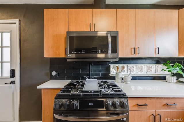 kitchen with light countertops, stainless steel microwave, gas range, and decorative backsplash