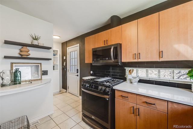 kitchen with light countertops, stainless steel microwave, backsplash, gas stove, and light tile patterned flooring