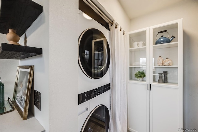 clothes washing area featuring stacked washer and dryer and laundry area