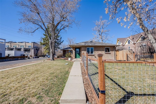 view of front facade with brick siding, fence, and a front lawn