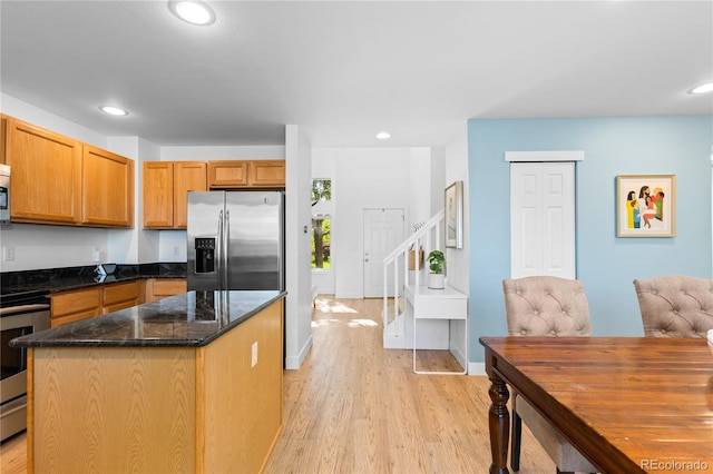 15963 Rock Crystal Dr, Parker, CO 80134 - kitchen with appliances with stainless steel finishes, light wood finished floors, a center island, dark stone counters, and recessed lighting