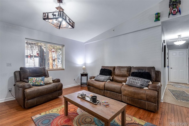 living room featuring vaulted ceiling, hardwood / wood-style floors, and an inviting chandelier