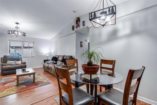 dining area featuring vaulted ceiling, an inviting chandelier, and light hardwood / wood-style flooring