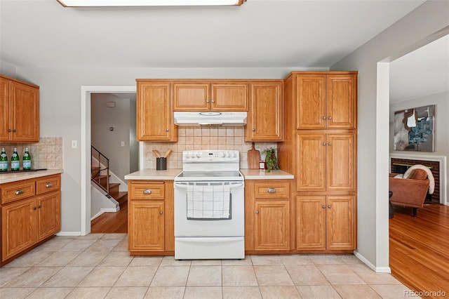 1905 S Linden Ct, Denver, CO 80224 - kitchen featuring white electric stove, under cabinet range hood, light countertops, decorative backsplash, and light tile patterned flooring