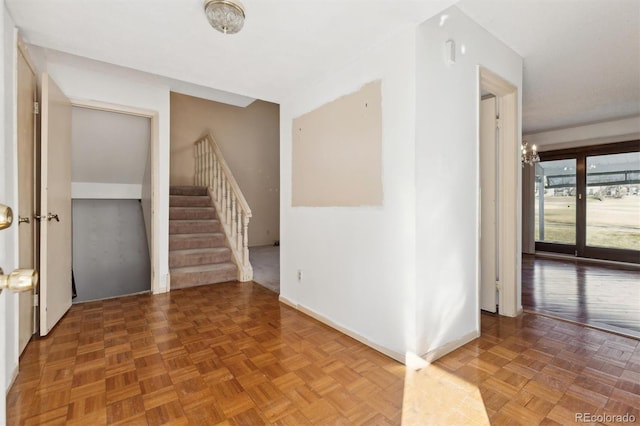 interior space featuring an inviting chandelier, baseboards, and stairway