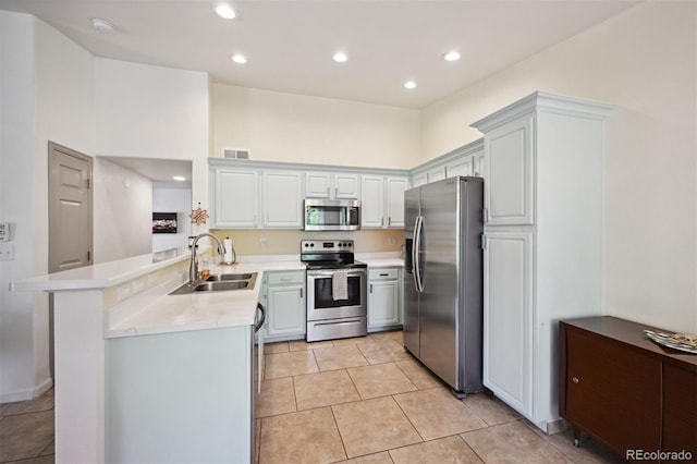 kitchen with kitchen peninsula, stainless steel appliances, sink, light tile patterned floors, and white cabinets