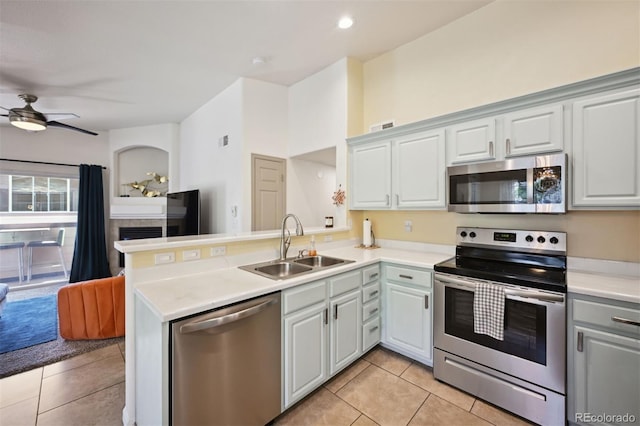 kitchen with light tile patterned flooring, sink, kitchen peninsula, and stainless steel appliances