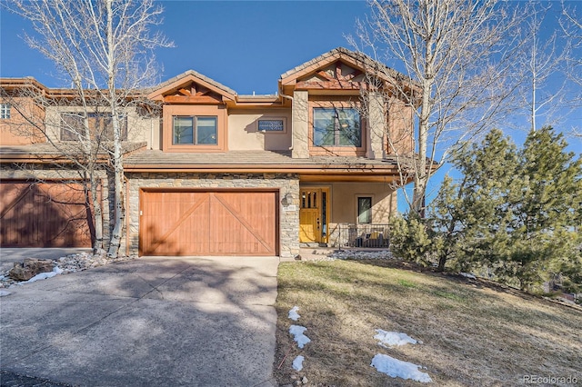 view of front facade with a porch, stone siding, a tiled roof, driveway, and stucco siding