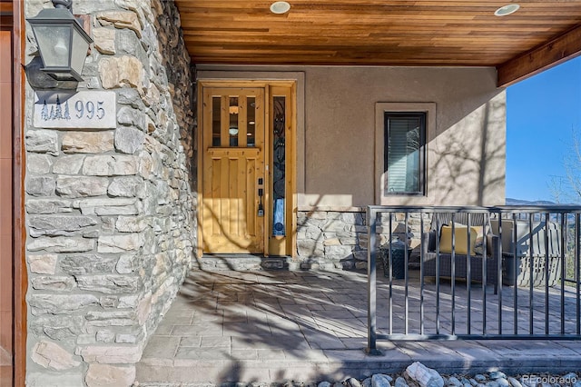 view of exterior entry featuring stone siding and stucco siding