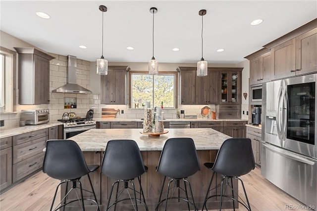 505 Rd P69, Bailey, CO 80421 - kitchen featuring appliances with stainless steel finishes, wall chimney range hood, a center island, tasteful backsplash, and recessed lighting