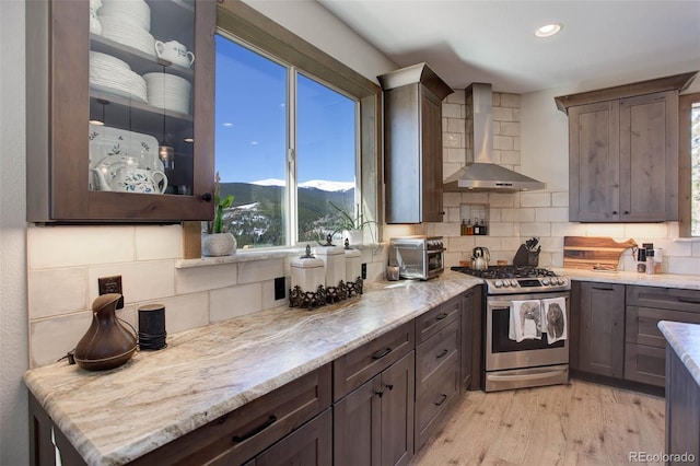 505 Rd P69, Bailey, CO 80421 - kitchen with wall chimney exhaust hood, stainless steel gas stove, a mountain view, backsplash, and recessed lighting