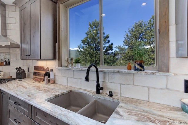 505 Rd P69, Bailey, CO 80421 - kitchen with decorative backsplash, gas range, a sink, light stone counters, and wall chimney exhaust hood