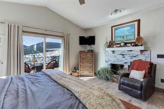 505 Rd P69, Bailey, CO 80421 - bedroom with wood finished floors, access to exterior, lofted ceiling, a fireplace, and ceiling fan