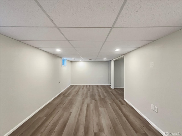 basement with hardwood / wood-style floors and a paneled ceiling