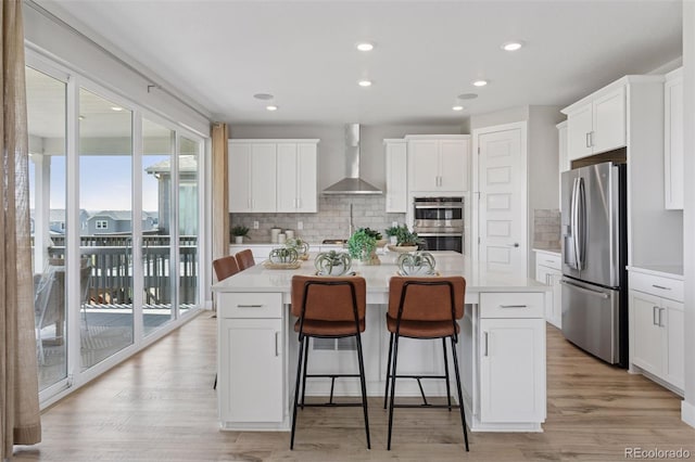 13334 Blue Amber Ct, Parker, CO 80134 - kitchen featuring appliances with stainless steel finishes, wall chimney exhaust hood, a center island with sink, white cabinetry, and recessed lighting