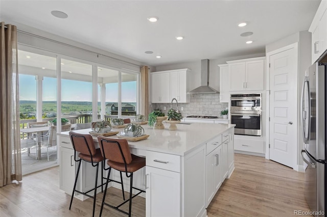 13334 Blue Amber Ct, Parker, CO 80134 - kitchen with wall chimney range hood, stainless steel appliances, backsplash, a center island with sink, and white cabinetry
