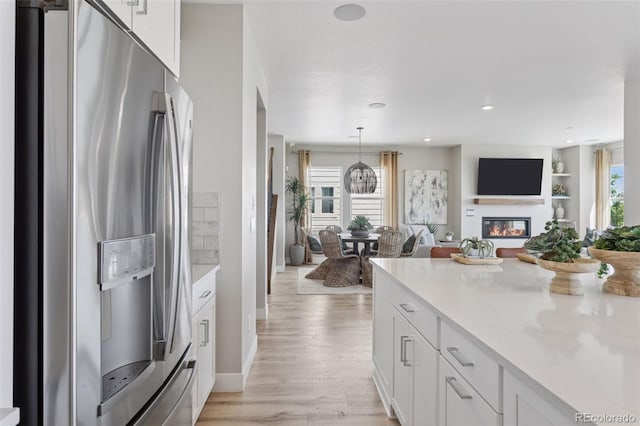 13334 Blue Amber Ct, Parker, CO 80134 - kitchen with stainless steel fridge with ice dispenser, open floor plan, white cabinets, light wood-style floors, and recessed lighting