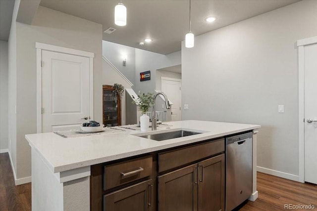 kitchen featuring dark hardwood / wood-style flooring, stainless steel dishwasher, sink, decorative light fixtures, and a center island with sink