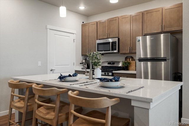 kitchen with a kitchen breakfast bar, a kitchen island with sink, and stainless steel appliances