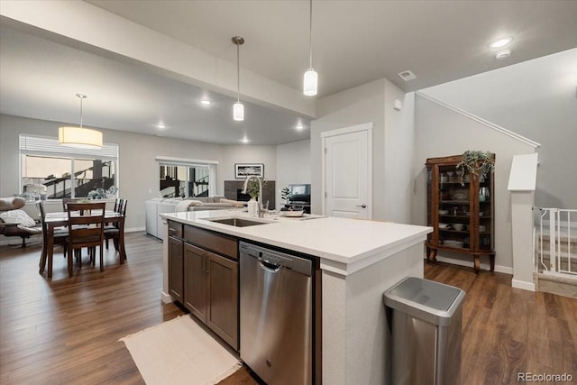 kitchen featuring stainless steel dishwasher, dark hardwood / wood-style floors, pendant lighting, and a center island with sink