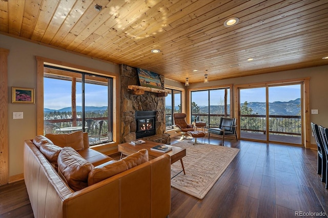 living room featuring a mountain view, a stone fireplace, wood ceiling, and dark hardwood / wood-style floors