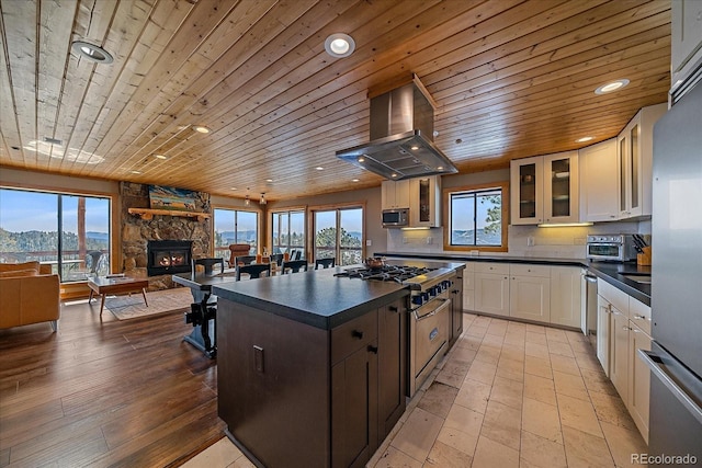 kitchen featuring wood ceiling, range hood, white cabinetry, a mountain view, and stainless steel appliances