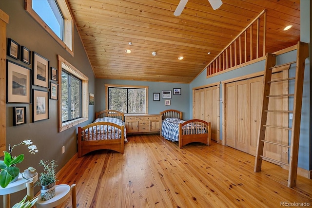 unfurnished bedroom with wooden ceiling, light hardwood / wood-style floors, two closets, and high vaulted ceiling