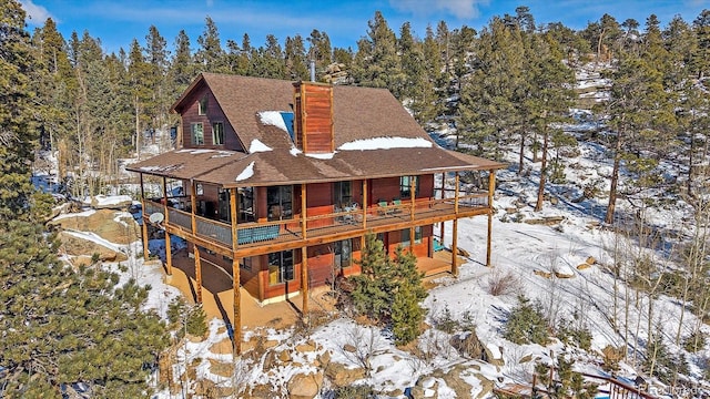 snow covered back of property featuring a wooden deck