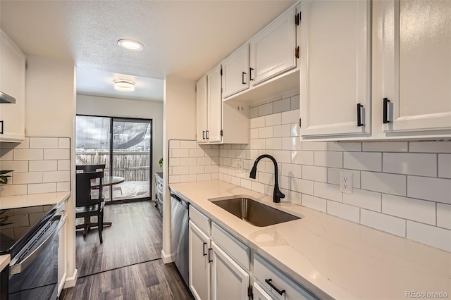 kitchen featuring dark wood-type flooring, sink, light stone counters, appliances with stainless steel finishes, and white cabinets