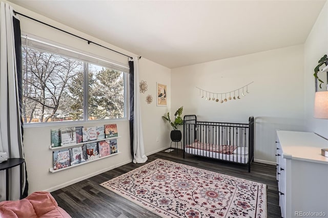 bedroom with a nursery area and dark hardwood / wood-style flooring