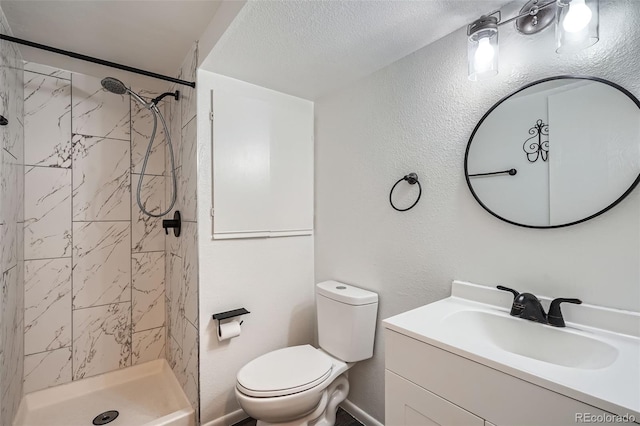 bathroom with vanity, tiled shower, and toilet