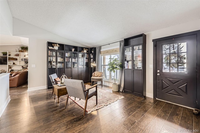 foyer entrance featuring a textured ceiling, dark hardwood / wood-style floors, and vaulted ceiling