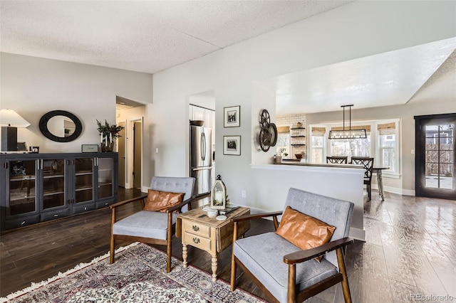 living area featuring dark wood-type flooring, a textured ceiling, and vaulted ceiling