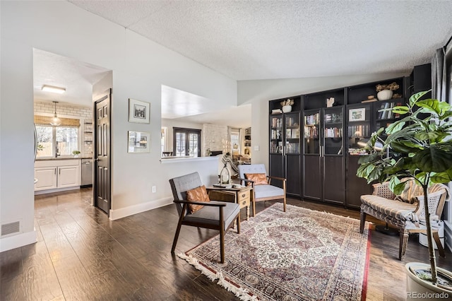 sitting room with lofted ceiling, a textured ceiling, dark hardwood / wood-style floors, and a wealth of natural light