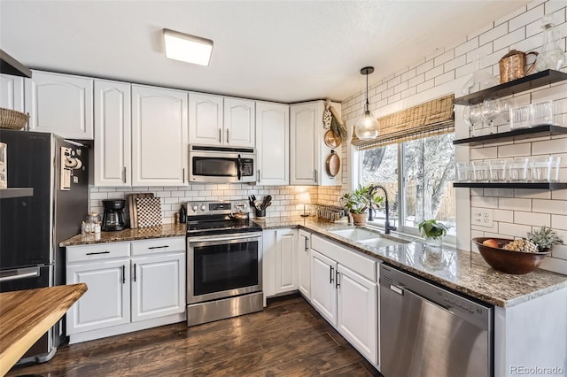 kitchen featuring white cabinetry, stainless steel appliances, and dark stone counters