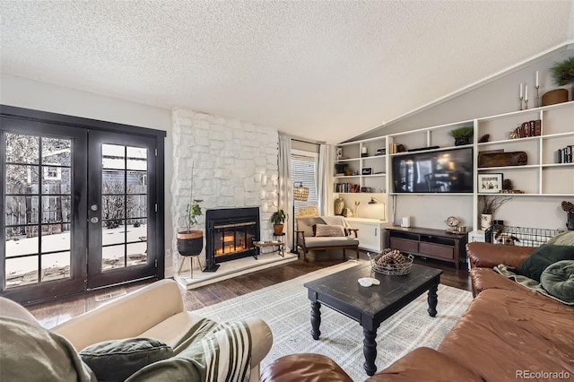 living room with a textured ceiling, lofted ceiling, wood-type flooring, french doors, and a fireplace