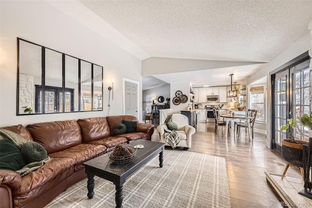 living room featuring hardwood / wood-style flooring, a textured ceiling, and lofted ceiling