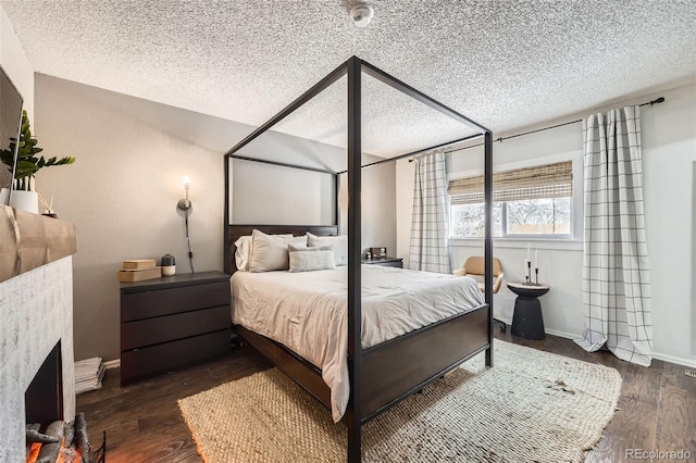 bedroom featuring a textured ceiling, a fireplace, and dark hardwood / wood-style flooring